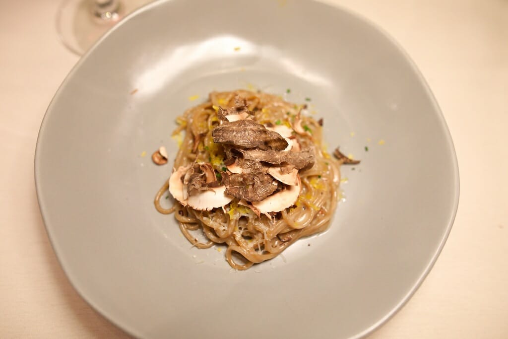 In a small pile, there is pasta, cheese, mushrooms, and cured egg yolk