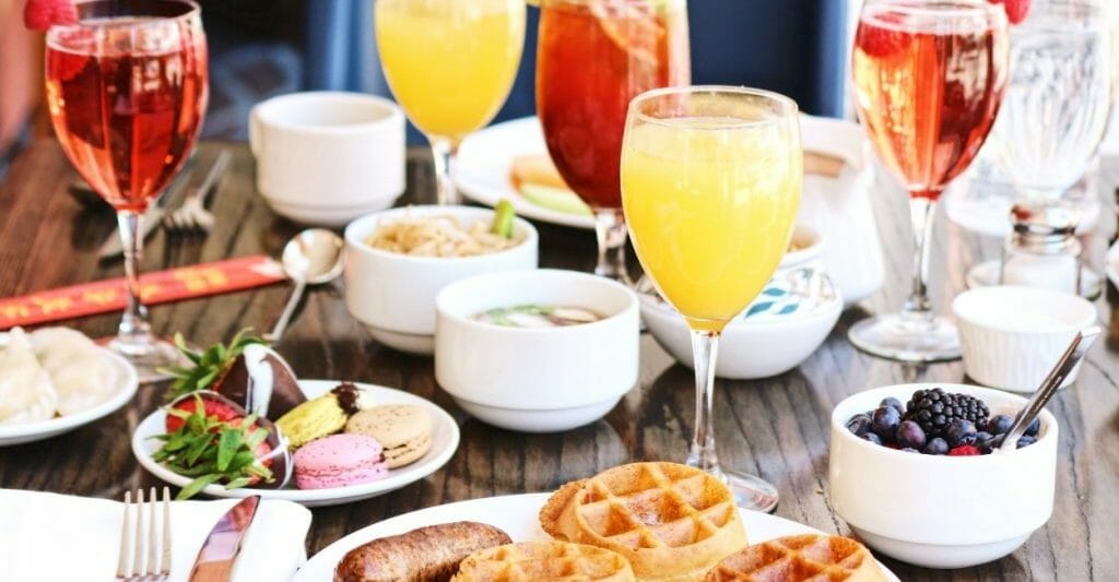 Best Brunch in San Diego - Table with brunch dishes like fruit, waffles, mimosas, coffee, and other drinks.