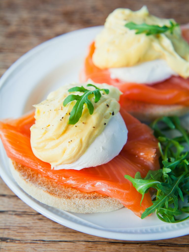 Eggs Benedict - Poached eggs with Hollandaise Sauce, fresh arugula and Smoked Salmon on English Muffin. Perfect Breakfast or lunch.