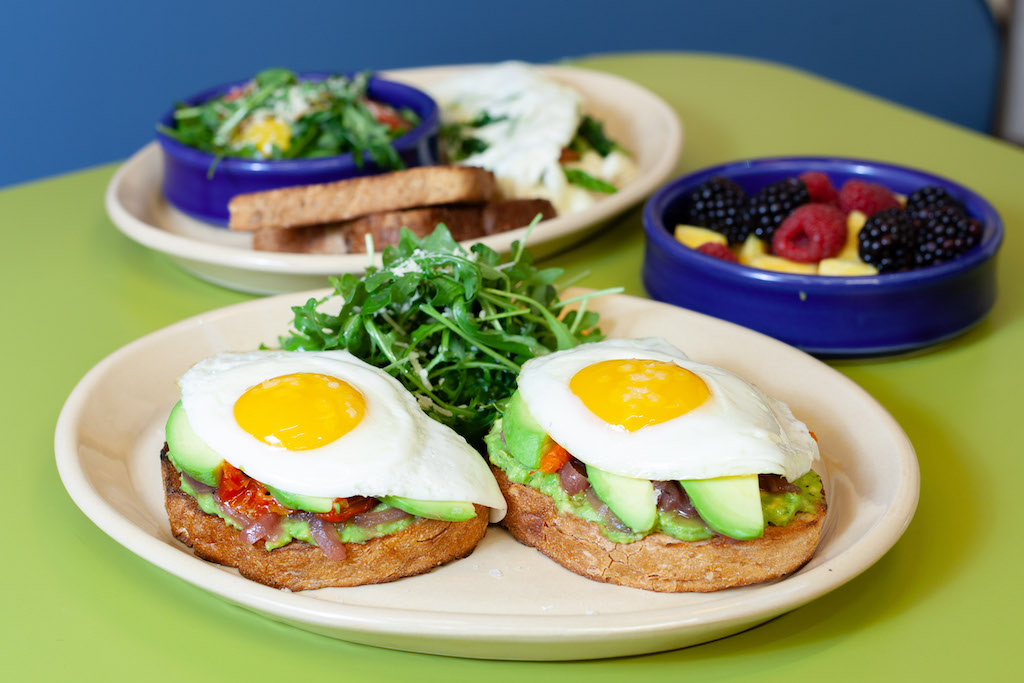 Avocado toast with two sunny side up eggs and tomato
