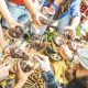 Top view of friend hands toasting red wine glass and having fun outdoor cheering at picnic winetasting - Young people enjoying summer time together at lunch bbq garden party - Youth friendship concept