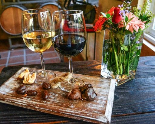 Red and white whine glasses with a tray of small snacks in front