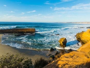 View of La Jolla Beach with a concrete fortification and cliffs surrounding a small sand beach with sea lions
