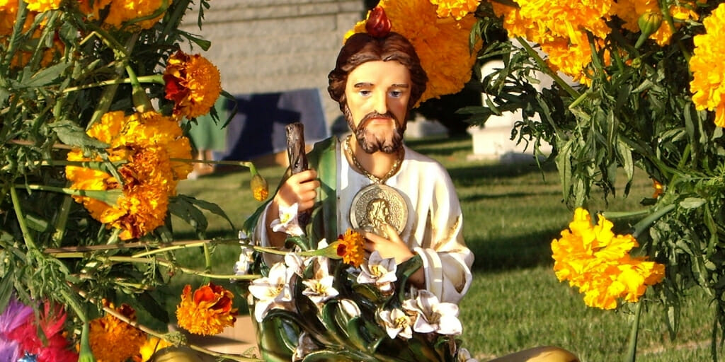Cemetery decorated with flowers and Jesus statue for Day of the Dead