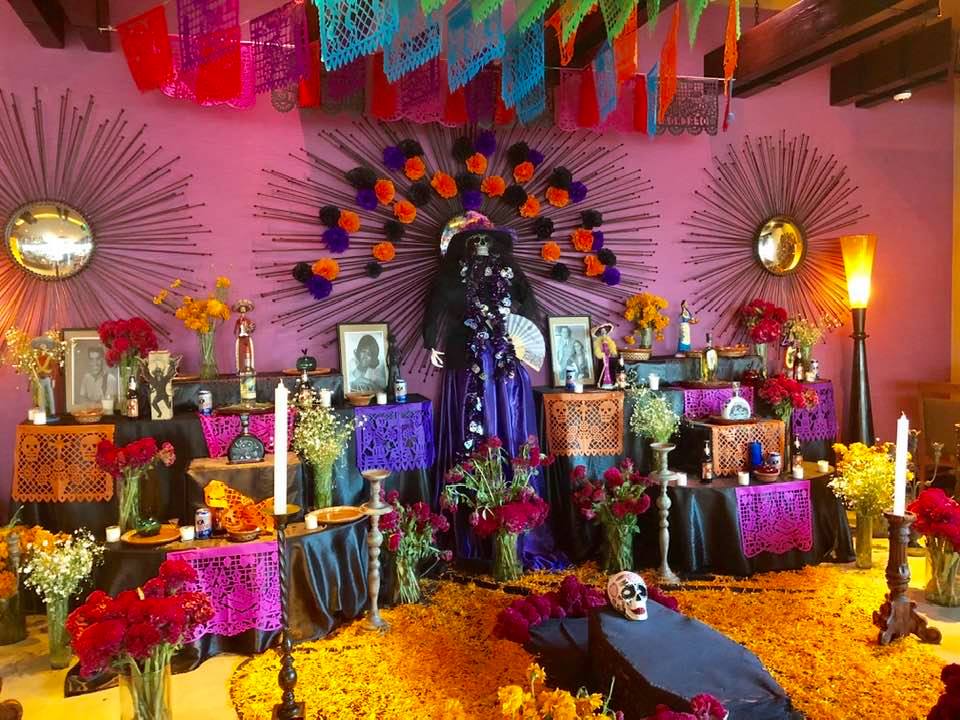Traditional alter for day of the dead with colorful decorations, photos of the dead, flowers, decoration, favorite foods, and candles