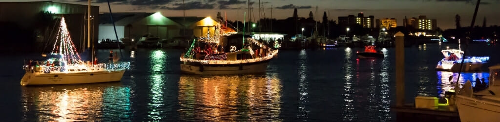 Boats decorated with Christmas lights passing through a channel