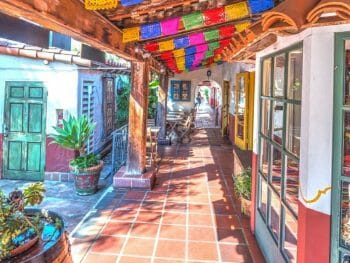 store fronts with terracotta tile walkway, white walls, wood covered path and colorful paper garlands