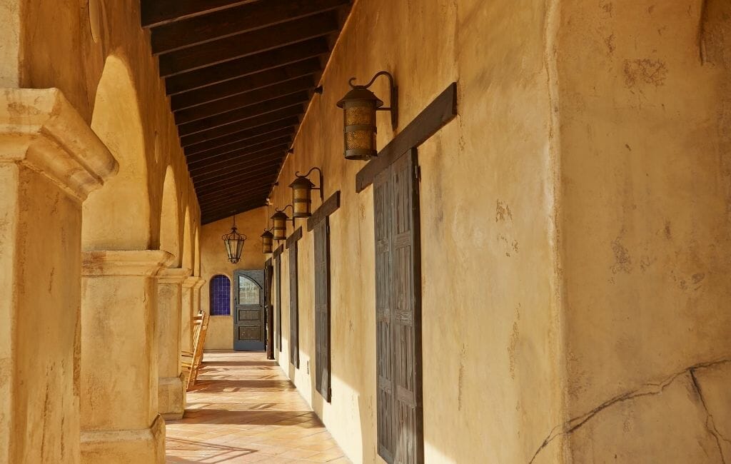 Historic military building with tan colored walls, dark wood doors along an arched covered walk way at the Mormon Battalion Old Town San Diego California