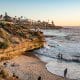 Orange sandstone cliffs in La Jolla with small beach during sunset