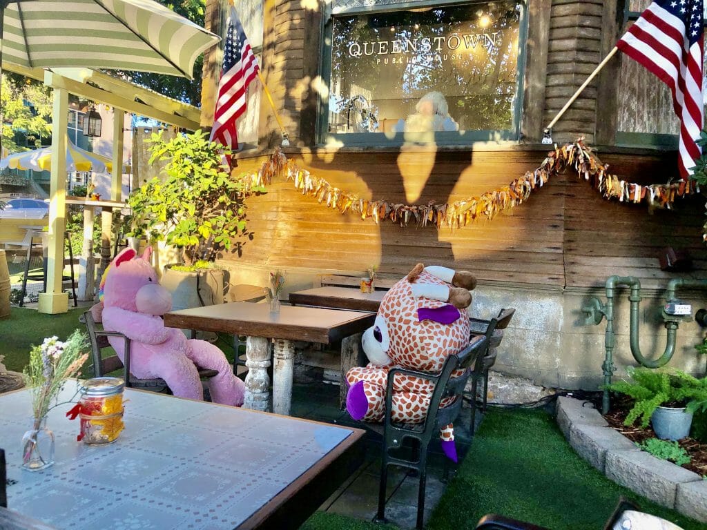outdoor patio at Queenstown Pub San Diego with stuffed animals seated on every other table for social distancing measure