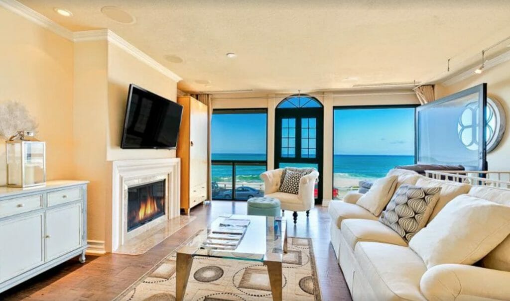 Elegant Oceanfront Vacation Home Living Room with white couch and fireplace and view of the ocean