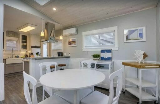 dining room with white table and 4 chairs with kitchen in the background