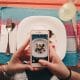 two female hands taking photo of plate of food on a colorful table setting