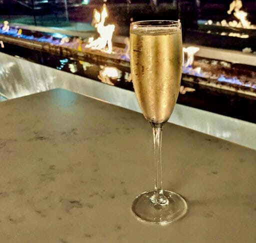 Champagne flute with a gas fire place in the background (blurred) after dark