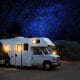RV with lights on with a stary night sky in the background