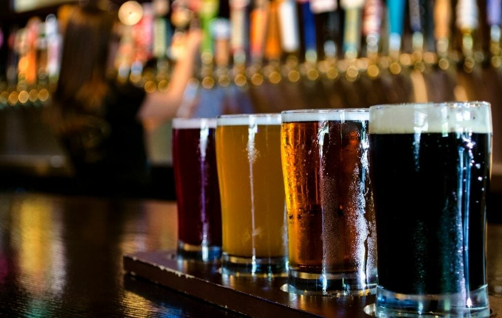 flight of Craft Beers in the foreground with a bar blurry in the background Tijuana-Things To Do in Tijuana
