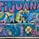 blue and purple wall mural with iconic things that Tijuana is known for, like the CECUT cultural center, the Tijuana zonkey etc