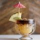 Mai Tai cocktail in a Tiki-inspired glass with slice of pineapple and pink umbrella