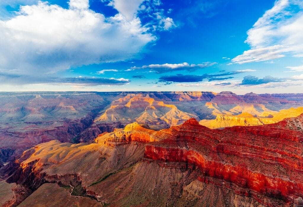 Blue sky and fluffy white clouds over the red rocks of the Grand canyon