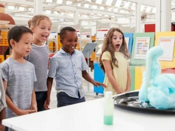 Children standing around a table watching a science experiment. Things to do in San Diego on a rainy day.