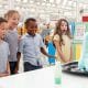 Children standing around a table watching a science experiment. Things to do in San Diego on a rainy day.