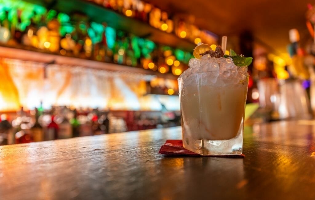 tropical cocktail on a bar with bottles and lights in the background