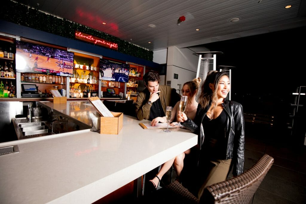 2 women and 1 man sitting on a white bar at night
