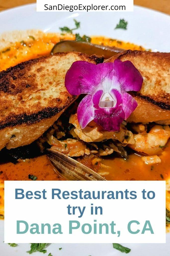 Chioppino seafood stew with garlic plate and decorated with a purple orchid - white box with text overlay: Best Restaurants to try in Dana Point, CA - If you&rsquo;re into great seafood and dining with a view, Dana Point Harbor restaurants have you covered. Here are our favorite ones: