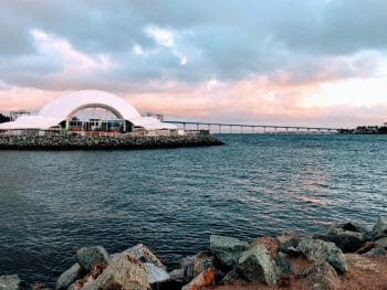 White shell-shaped concert hall on the embarcadero in San Diego Bay with the Coronado Bay Bridge in the Background - The Rady Shell Symphony San Diego