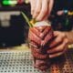 Hand reaching cocktail in tiki glass over bar counter