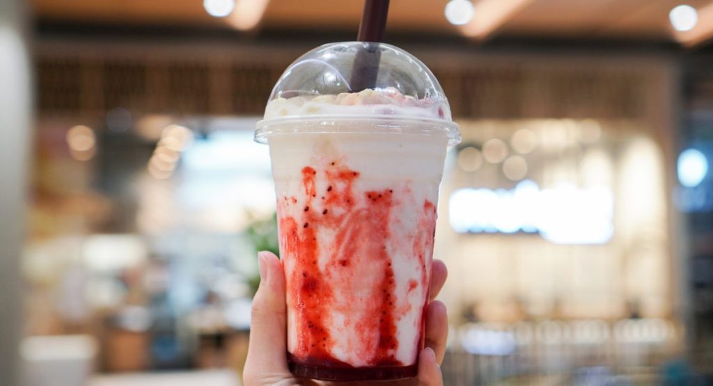 A person holding strawberry ice cream shake 