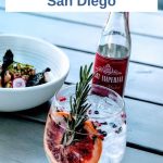 Cocktail with blood orange and rosemary with tonic bottle and bowl with salad