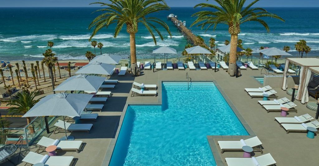 view over rooftop hotel pool at the Mission Resort Oceanside Hotels with lounge chairs with the pacific ocean in the background