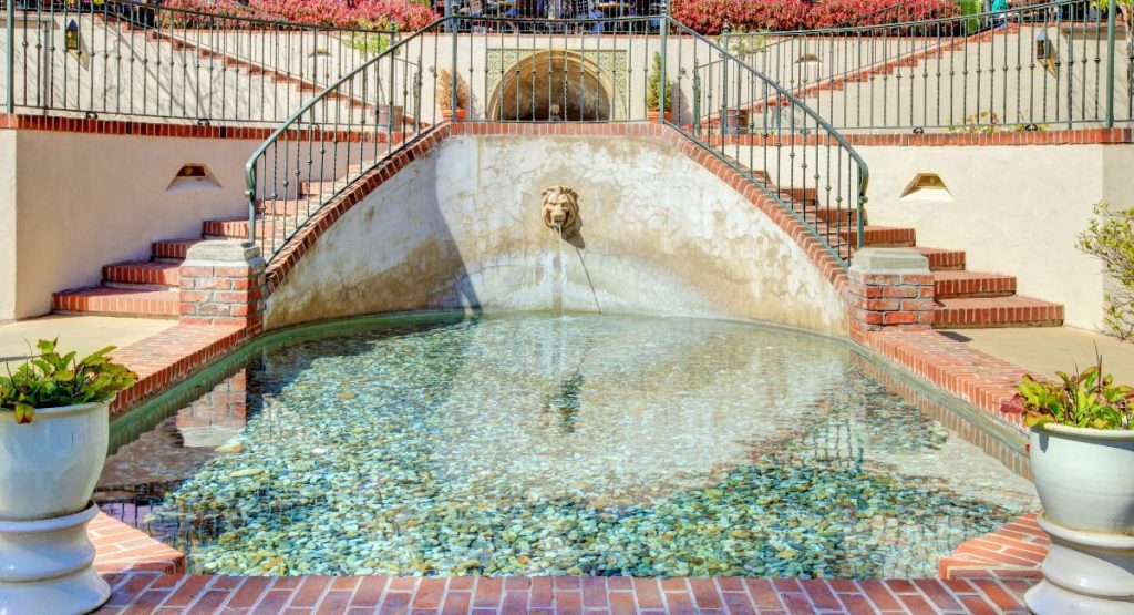 Fountain in the center, with wall in the background and stairs leading up on both sides