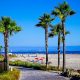 Palm tree lined path along white sand beach overlooking Pacific Ocean on sunny summer day with Hotel del Coronado in distance. Coronado Island, San Diego in July.