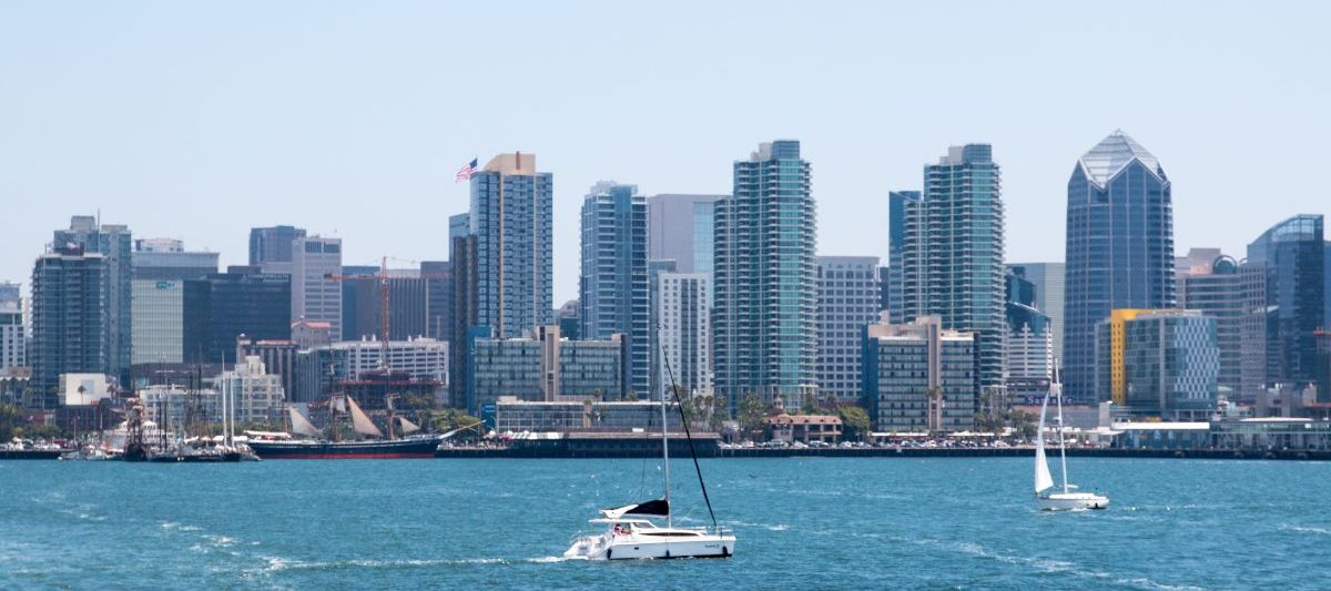 Sail boats on blue water of San Diego Bay with expansive downtown San Diego skyline in background on sunny day. September in San Diego.