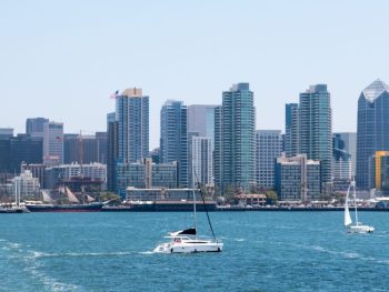 Sail boats on blue water of San Diego Bay with expansive downtown San Diego skyline in background on sunny day. September in San Diego.