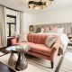 Modern, boutique hotel room with plush decor, pink couch, curtains, plants, and modern lighting. Orli La Jolla Boutique Hotels in San Diego.
