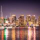 City skyline reflecting on water at night, boats sit on the colorful bay. San Diego skyline at night, Things to do in San Diego in November.