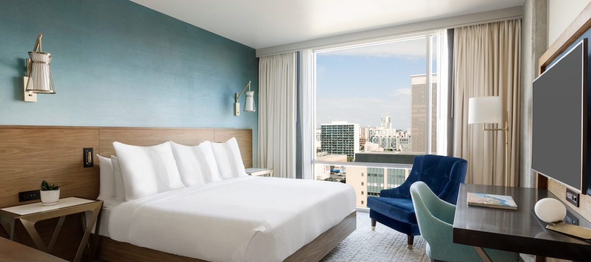 Hotel guest room with king size bed, TV, and small sitting area, room overlooks downtown San Diego. Carte Hotel San Diego, 4 Star Hotels San Diego.