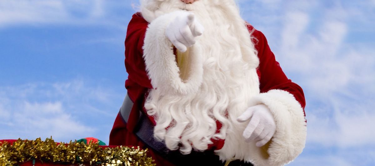 Santa Clause riding on christmas parade float pointing fingers