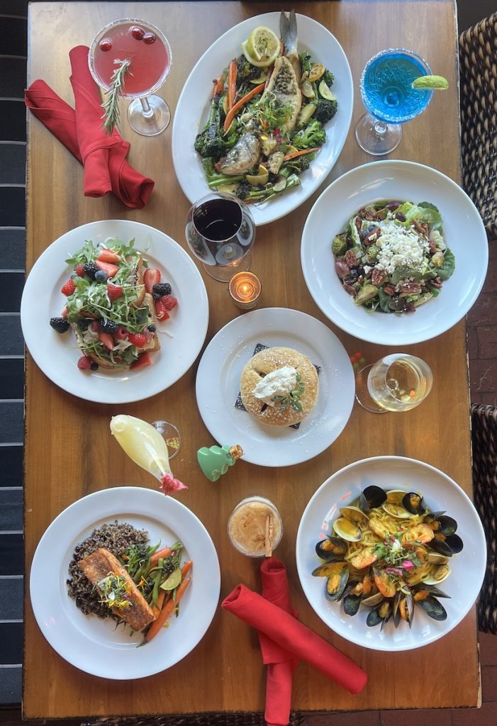 Restaurant table full of Italian dishes and cocktails in restaurant, San Diego dog friendly restaurants.
