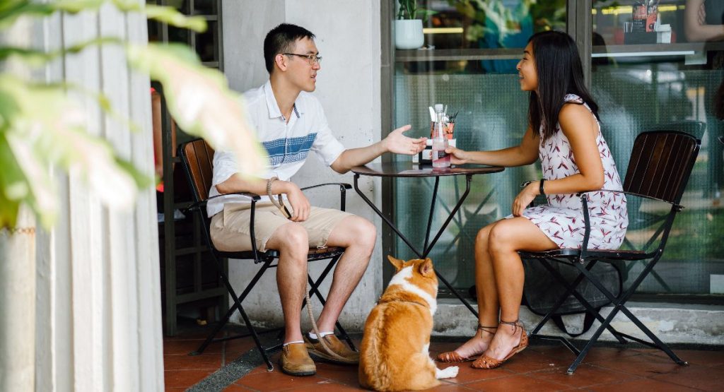 couple and corgi dog sitting at a Dog friendly restaurants San Diego