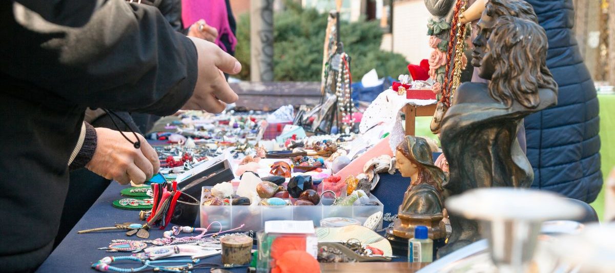 People looking at jewelry and goods on outdoor table at swap meet. Flea Market San Diego.