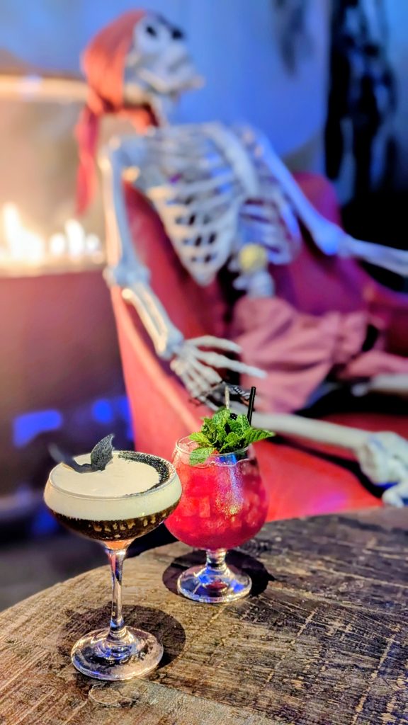 Halloween cocktails on table in front of pirate skeleton on chair