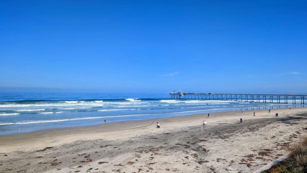 La Jolla Shores Beach on a sunny day with Scripps Pier in the background