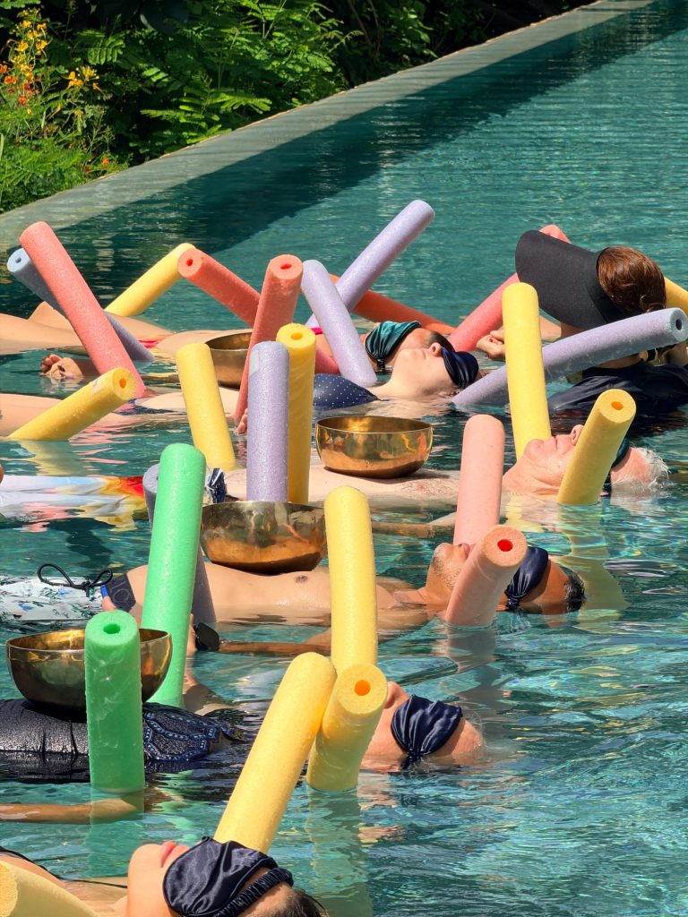 people floating with pool noodles in pool